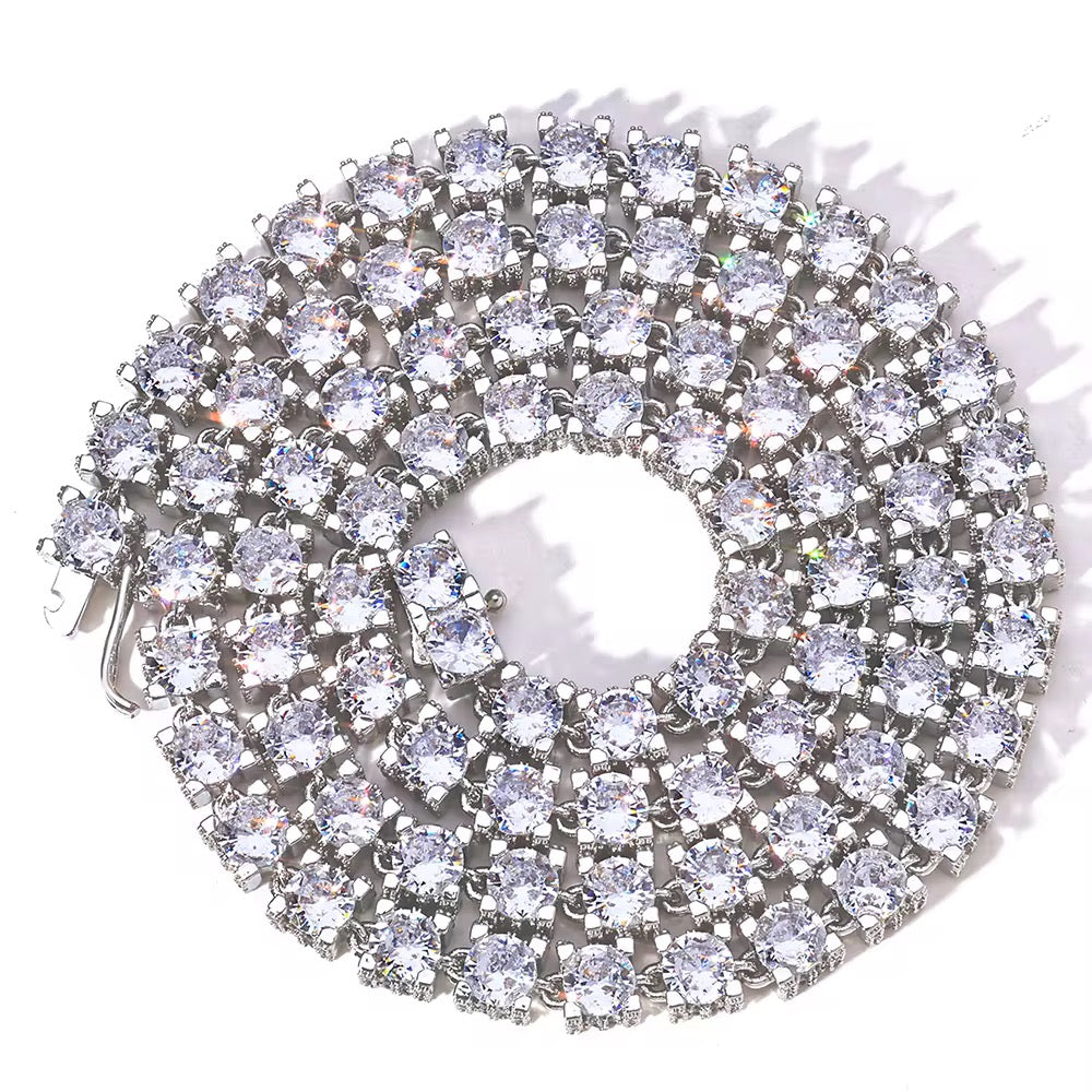 Circular silver brooch with clear gemstones on a white background

