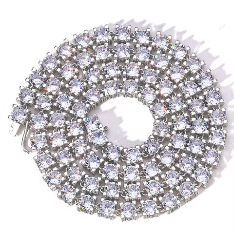 Circular silver brooch with clear gemstones on a white background

