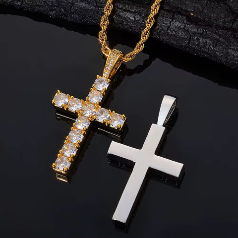 Two cross pendants, one gold and one silver, on a dark surface